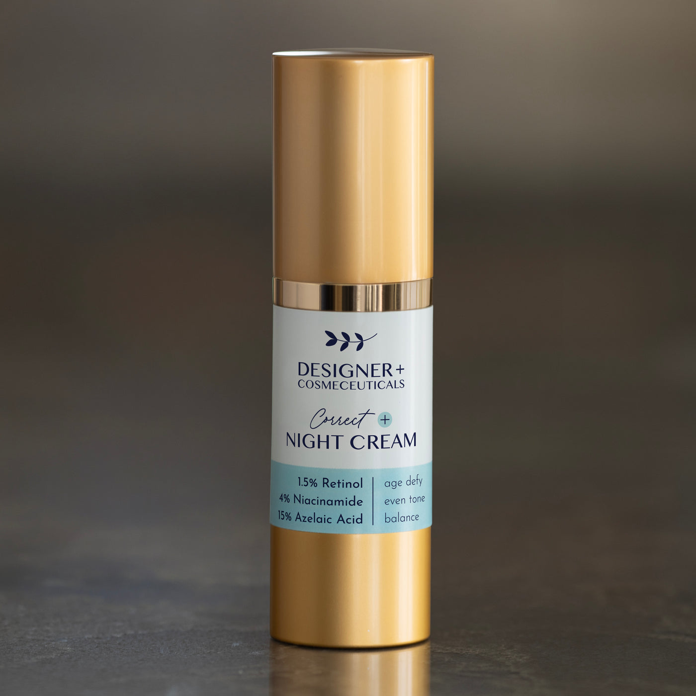 Designer+ Cosmeceuticals Correct+ Night Cream with 1.5% retinol, 4% niacinamide, and 15% azelaic acid in a gold and white airless pump bottle, on a reflective surface with a dark background