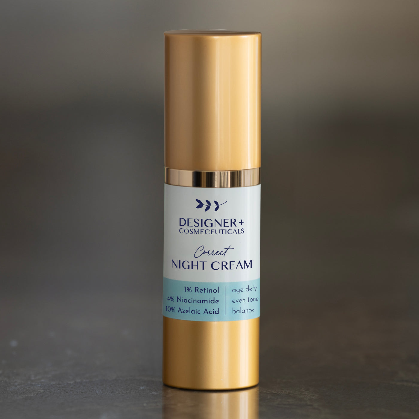 Designer+ Cosmeceuticals Correct Night Cream with 1% retinol, 4% niacinamide, and 10% azelaic acid in a gold and white airless pump bottle, on a reflective surface with a dark background